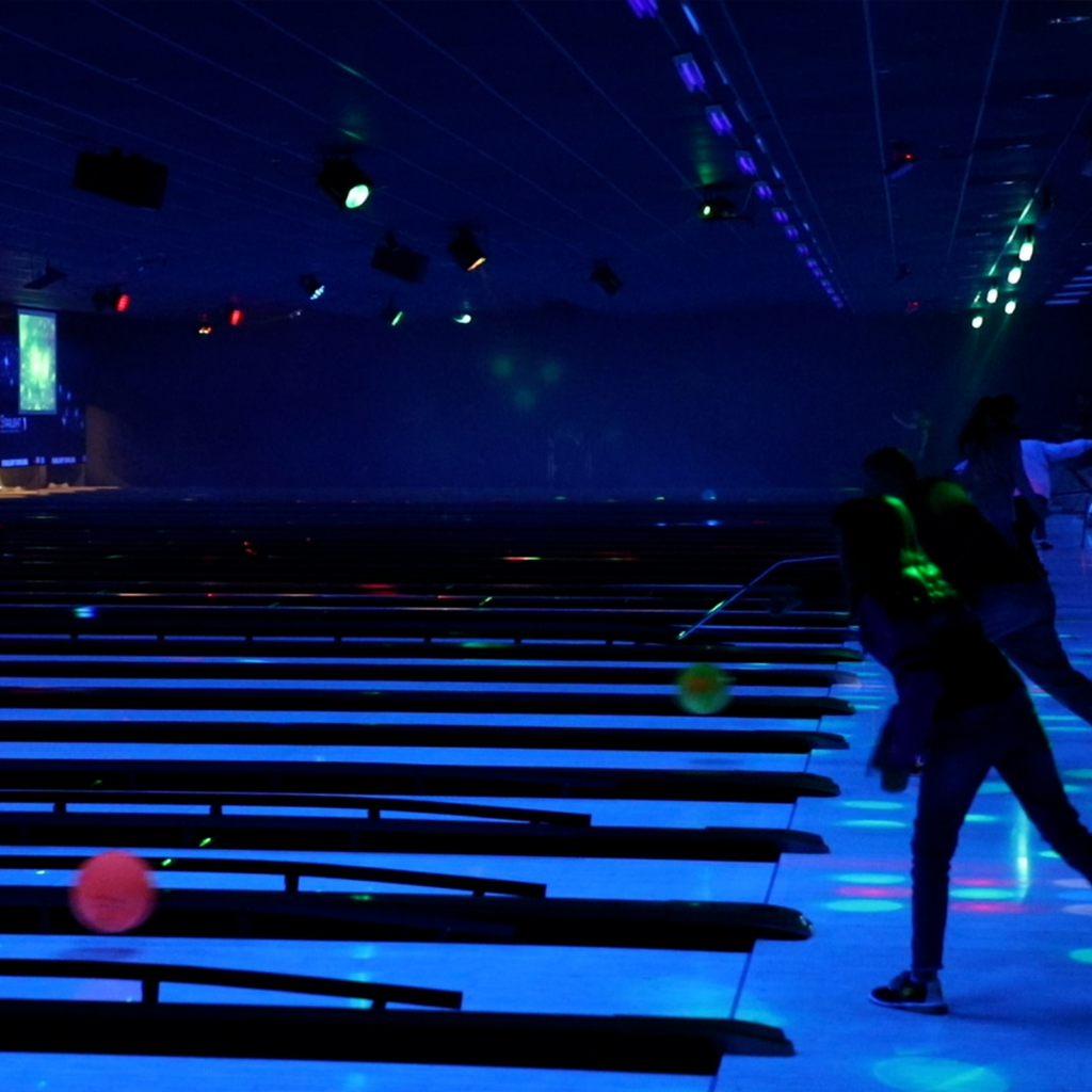 People bowling under black lights