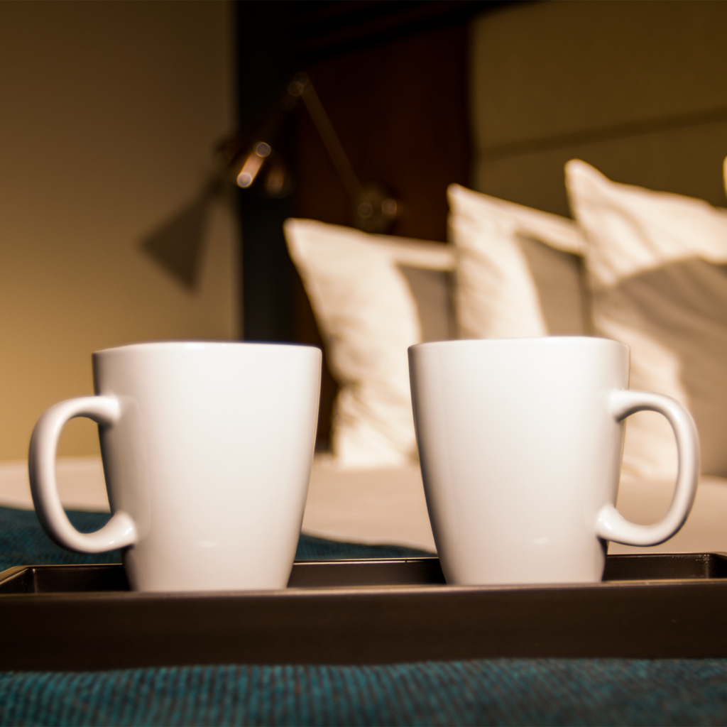 Two coffee cups on a bed